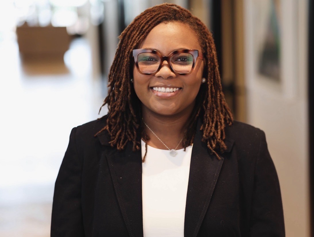 Portrait of Marissa Pittman smiling, wearing glasses and a black blazer